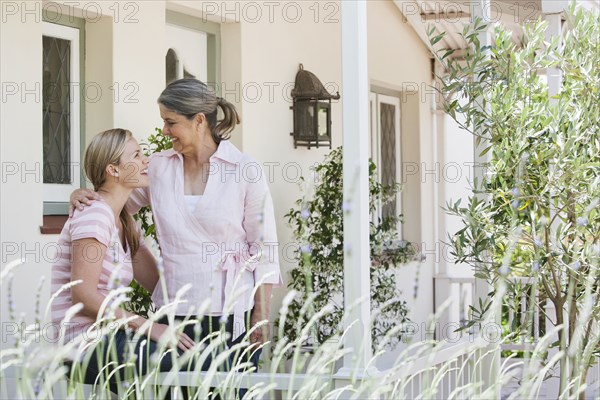 Caucasian mother and daughter talking on porch