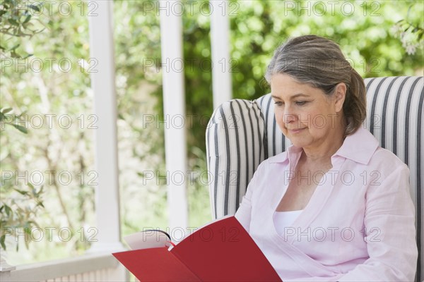 Senior Caucasian woman reading on porch