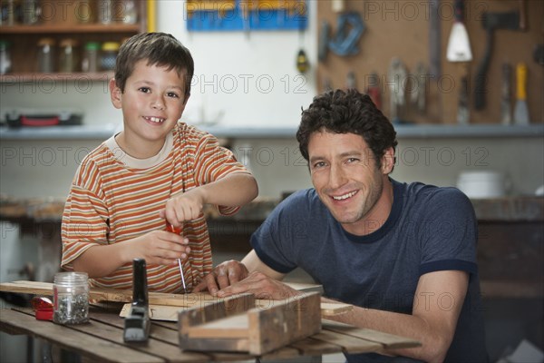 Caucasian father and son working in woodshop