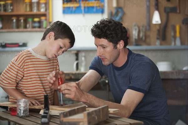 Caucasian father and son working in woodshop