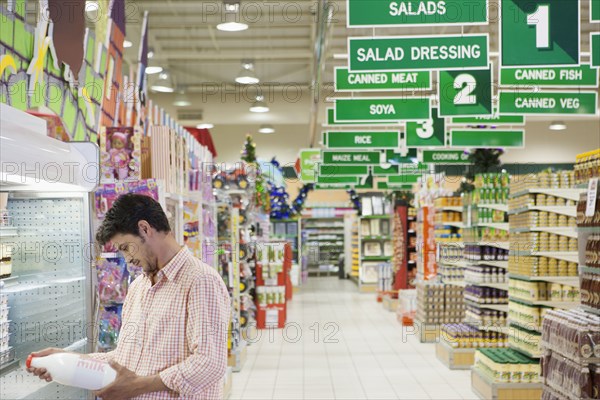 Caucasian man reading label in grocery store