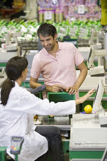 Caucasian man talking to cashier in grocery store