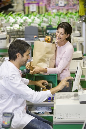 Caucasian woman talking to clerk in grocery store