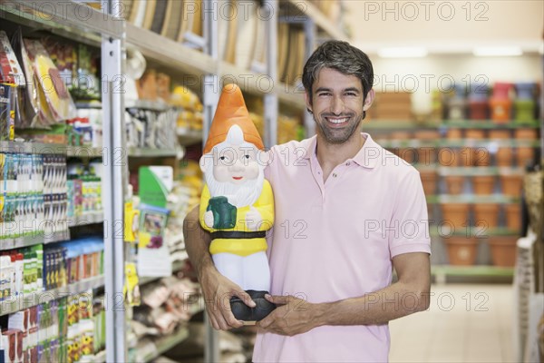 Caucasian man carrying garden gnome in hardware store