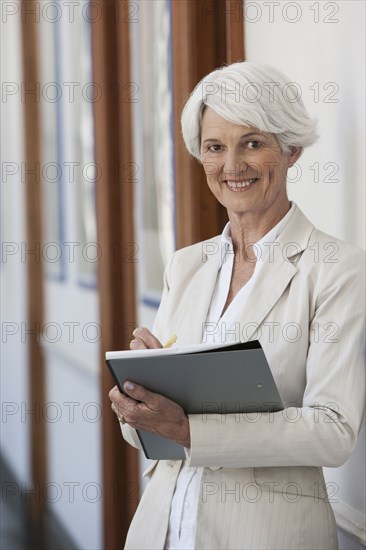 Senior Caucasian businesswoman making notes in office