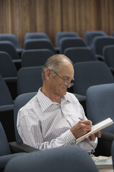 Senior Caucasian student taking notes in classroom