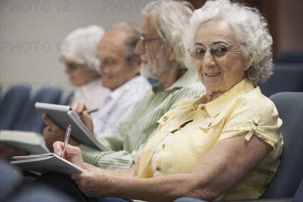 Senior Caucasian students taking notes in classroom