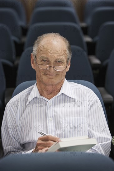 Senior Caucasian student taking notes in classroom