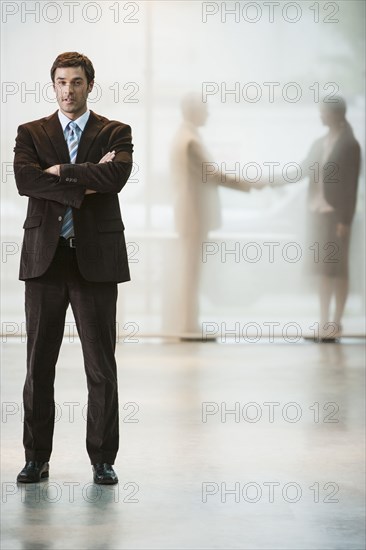 Businessman standing with arms crossed in office