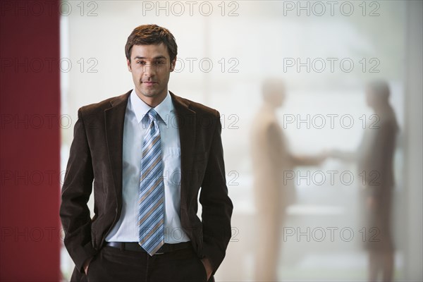 Businessman with hands in pockets in office