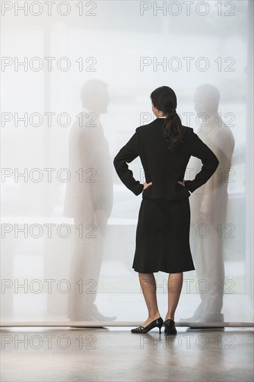 Businesswoman watching colleagues shake hands behind curtain