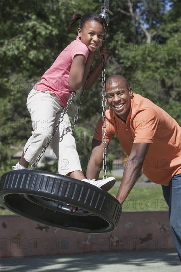 Father and daughter playing on tire swing