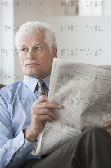 Caucasian businessman reading newspaper in office