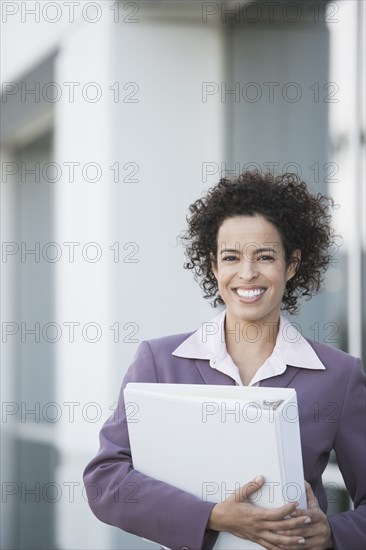 Hispanic businesswoman carrying large binder