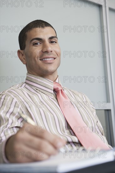 Hispanic businessman taking notes in office