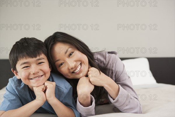 Asian mother and son laying on bed