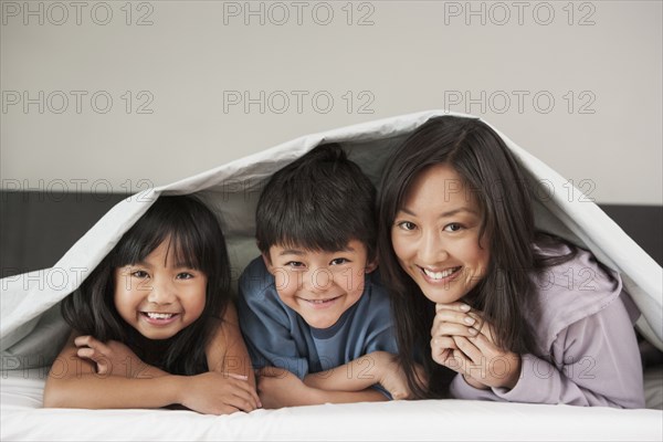 Mother and children laying under bed covers
