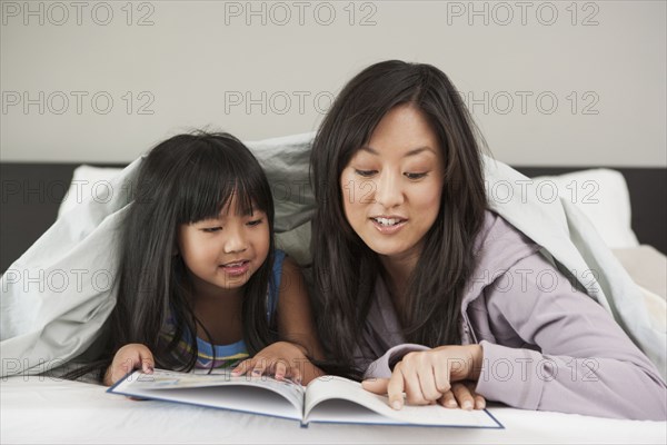 Mother and daughter reading in bed