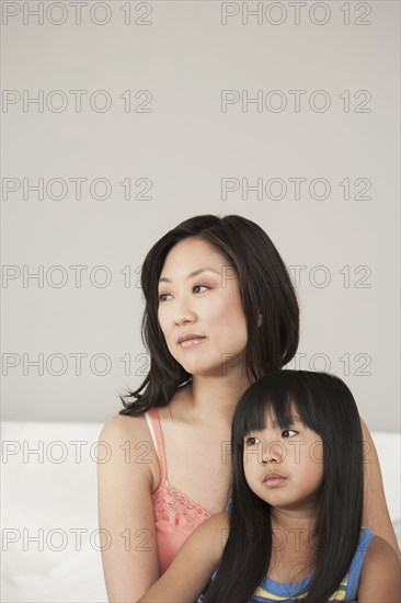 Mother and daughter sitting on bed