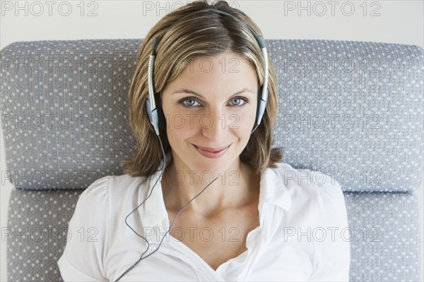 Woman listening to headphones in armchair