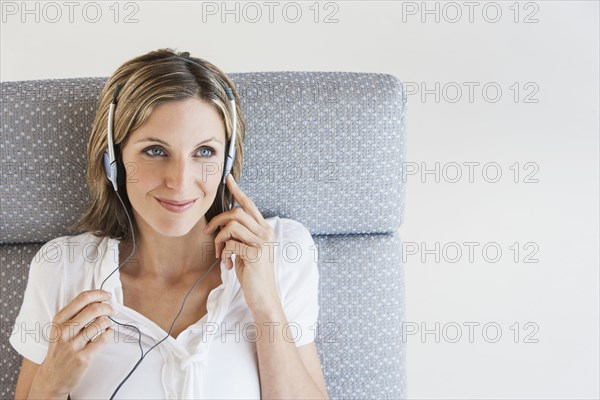 Woman listening to headphones in armchair