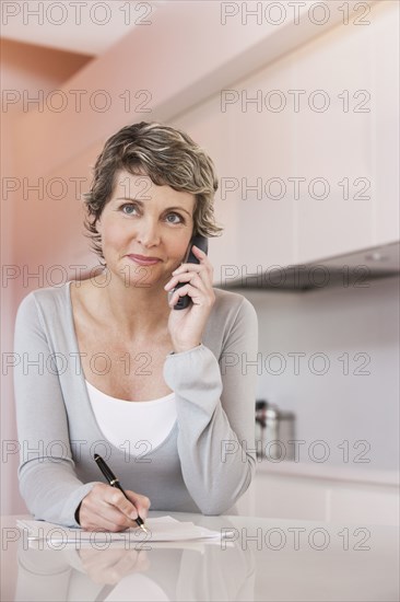 Woman taking notes and talking on phone