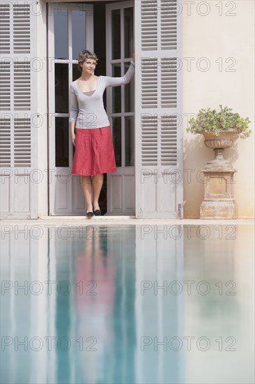 Woman in doorway overlooking swimming pool