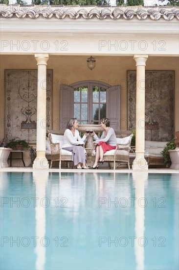 Women toasting each other by swimming pool