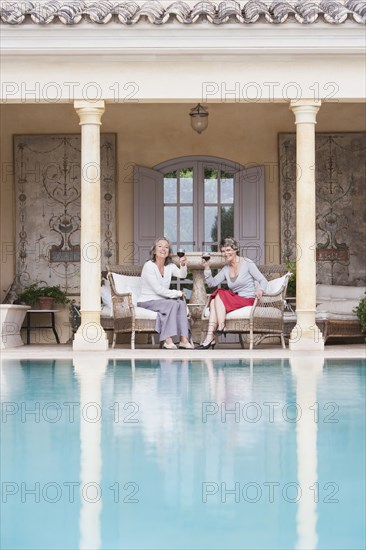 Women toasting each other by swimming pool