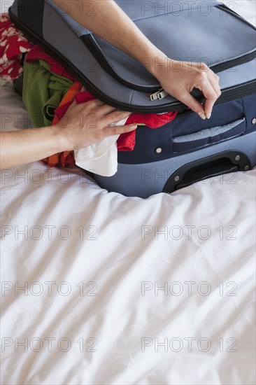 Woman packing suitcase on bed