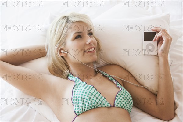 Woman listening to mp3 player on bed