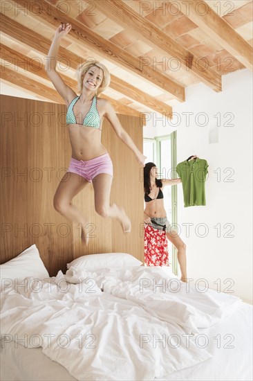 Woman jumping on bed