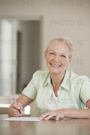 Senior Caucasian woman writing at table