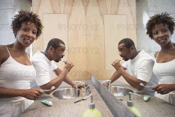 African American couple brushing teeth in bathroom