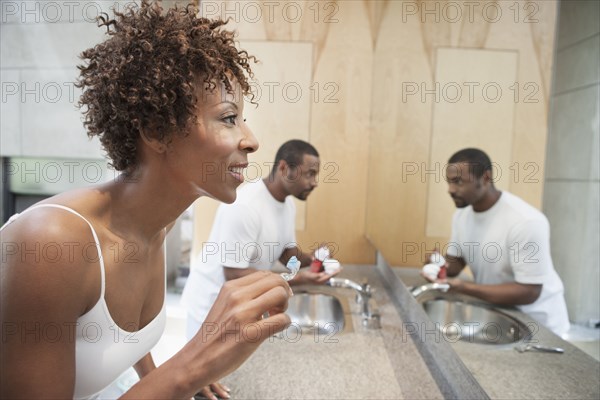 African American couple brushing teeth in bathroom