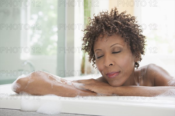African American woman relaxing in bubble bath