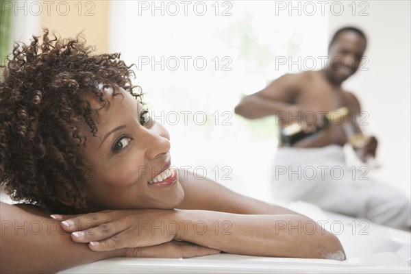 African American couple drinking champagne in bath