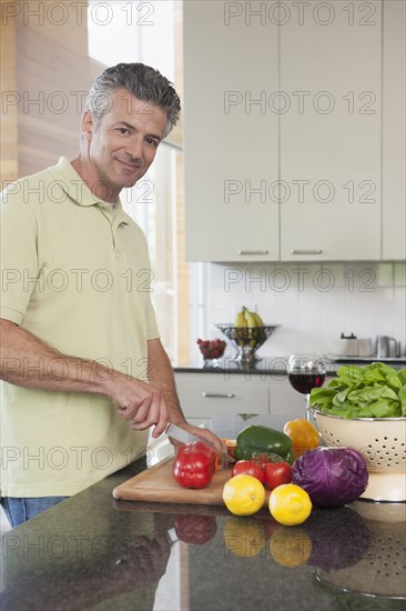 Hispanic man chopping vegetables in kitchen