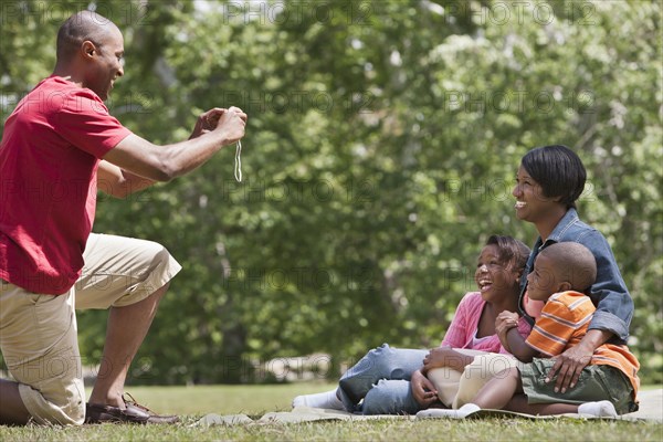 Family taking picture together on picnic blanket