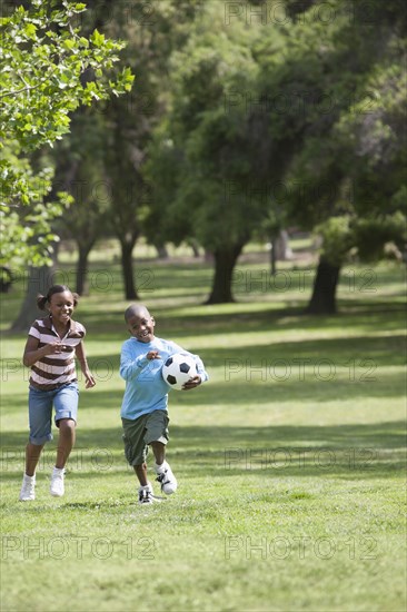African American children playing soccer in park