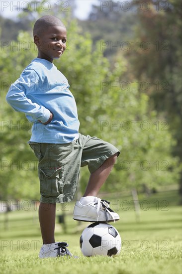 African American boy playing soccer in park