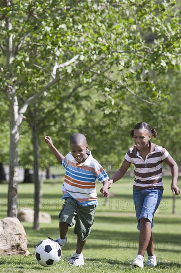 African American children playing soccer in park