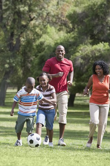 Family playing soccer in park