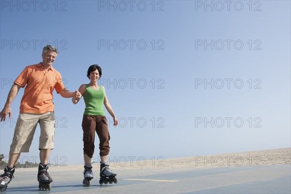 Caucasian couple rollerblading by beach