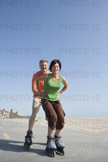 Caucasian couple rollerblading by beach