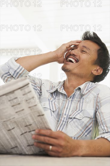 Asian man reading newspaper