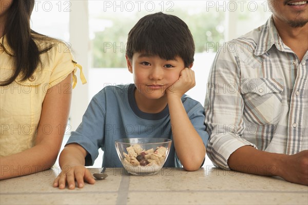 Boy sitting between parents at breakfast table