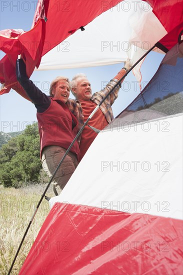 Senior Caucasian couple pitching tent in field