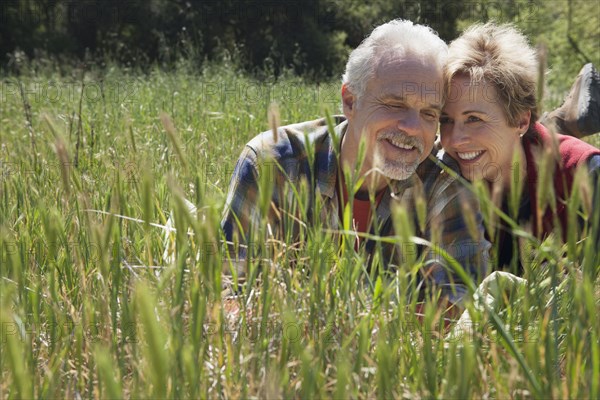 Senior Caucasian couple laying in tall grass