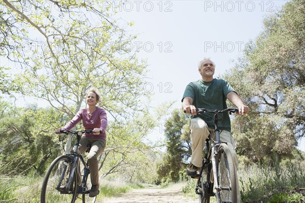 Senior Caucasian couple riding bicycles on rural path